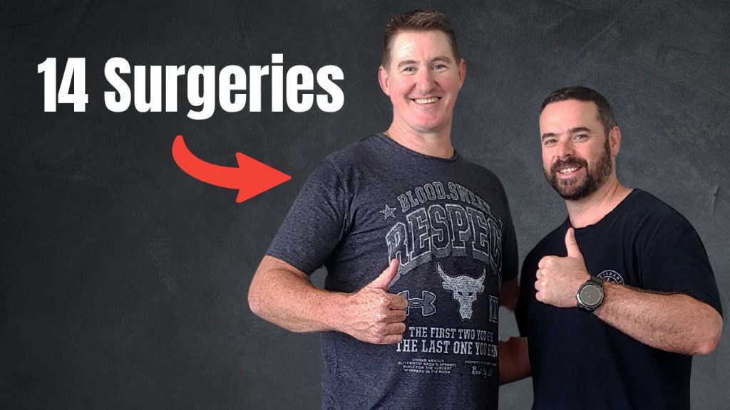 Two men posing and giving thumbs up in front of a dark backdrop, with bold text '14 Surgeries' and a red arrow pointing to them (video thumbnail).